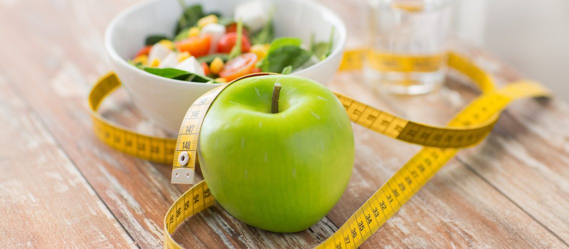 healthy eating, dieting, slimming and weigh loss concept - close up of green apple, measuring tape and salad
